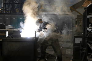 man in welding mask surrounded by welding smoke